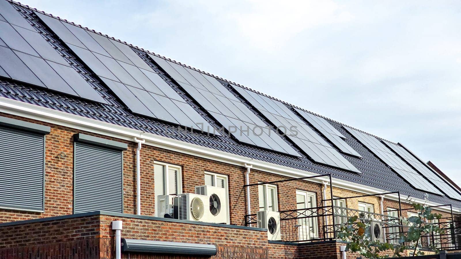 Newly build houses with solar panels attached on the roof against a sunny sky by fokkebok