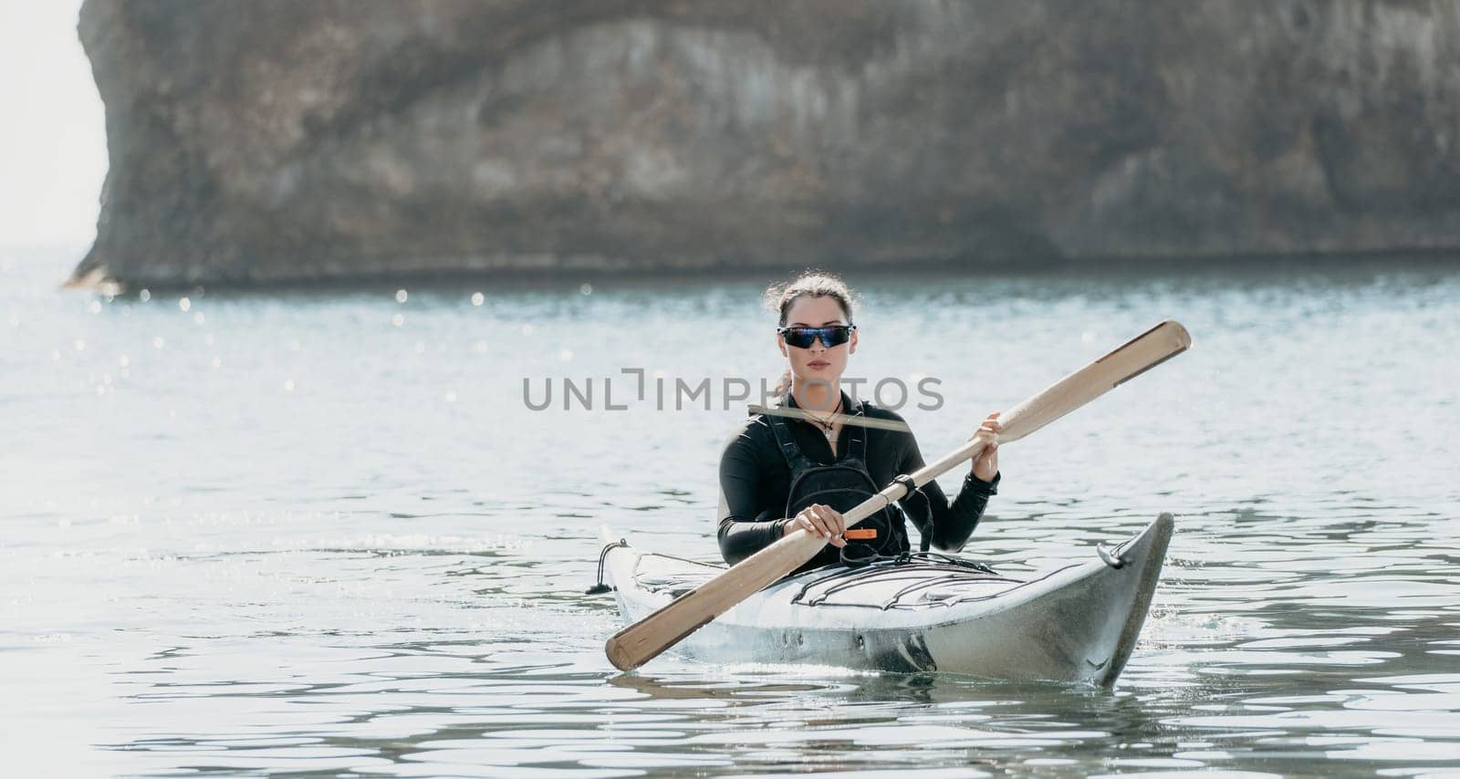 Woman sea kayak. Happy smiling woman in kayak on ocean, paddling with wooden oar. Calm sea water and horizon in background. Active lifestyle at sea. Summer vacation. by panophotograph