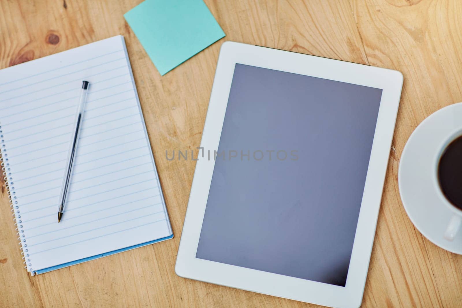 High angle, desk and tablet or paper in closeup with coffee, workspace with technology for background. Notebook, epad and above on table with drink in zoom, internet or app for marketing business.