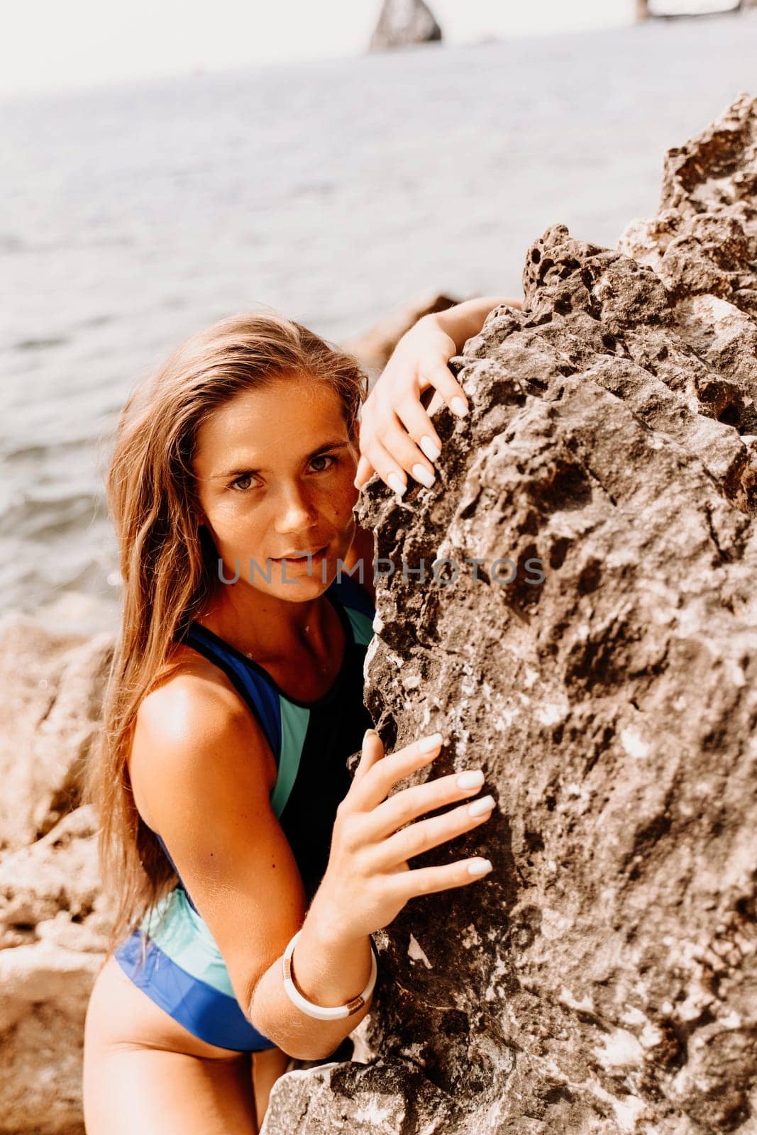 Woman beach vacation photo. A happy tourist in a blue bikini enjoying the scenic view of the sea and volcanic mountains while taking pictures to capture the memories of her travel adventure. by Matiunina