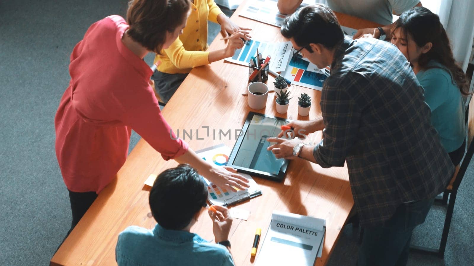 Top view of manager writing idea on sticky notes and explain idea about web design. Professional marketing team or programmer brainstorming idea while looking at tablet with color palette. Symposium.