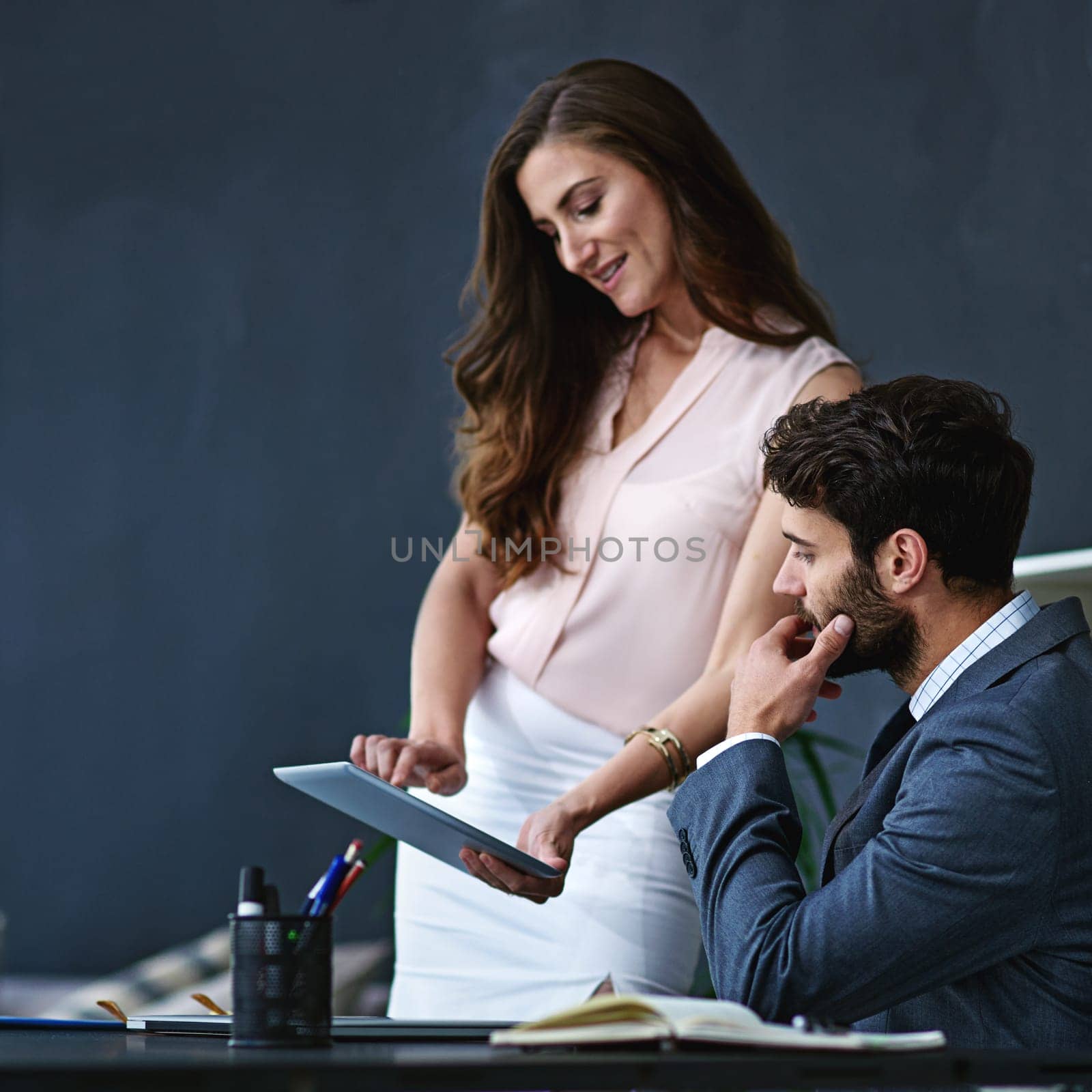 Business people, discussion and meeting with tablet for research, schedule or tasks at office. Young businessman with personal assistant or secretary showing or scrolling on technology for online app.