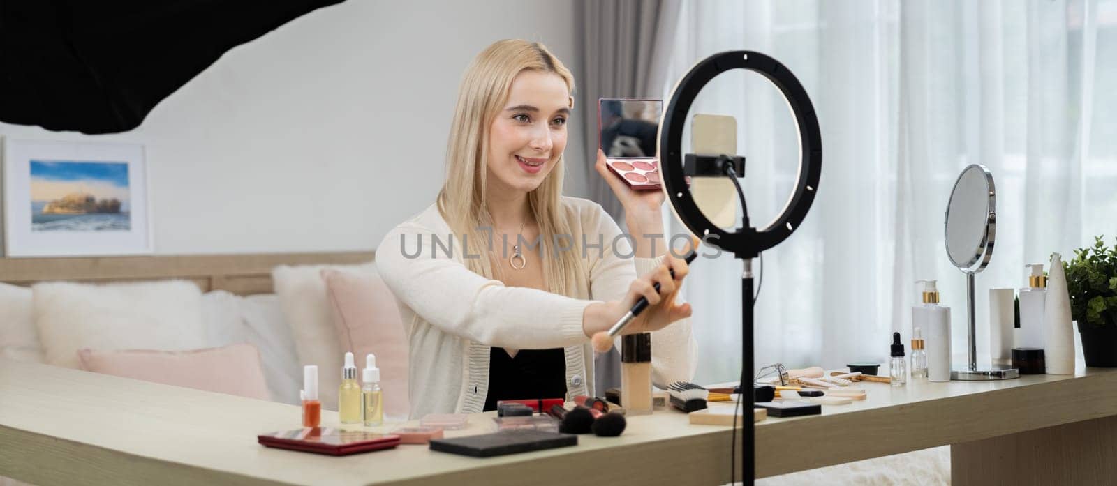 Young woman making beauty and cosmetic tutorial video content for social media. Beauty blogger smiles to camera while showing how to beauty care to audience or followers. Panorama Blithe