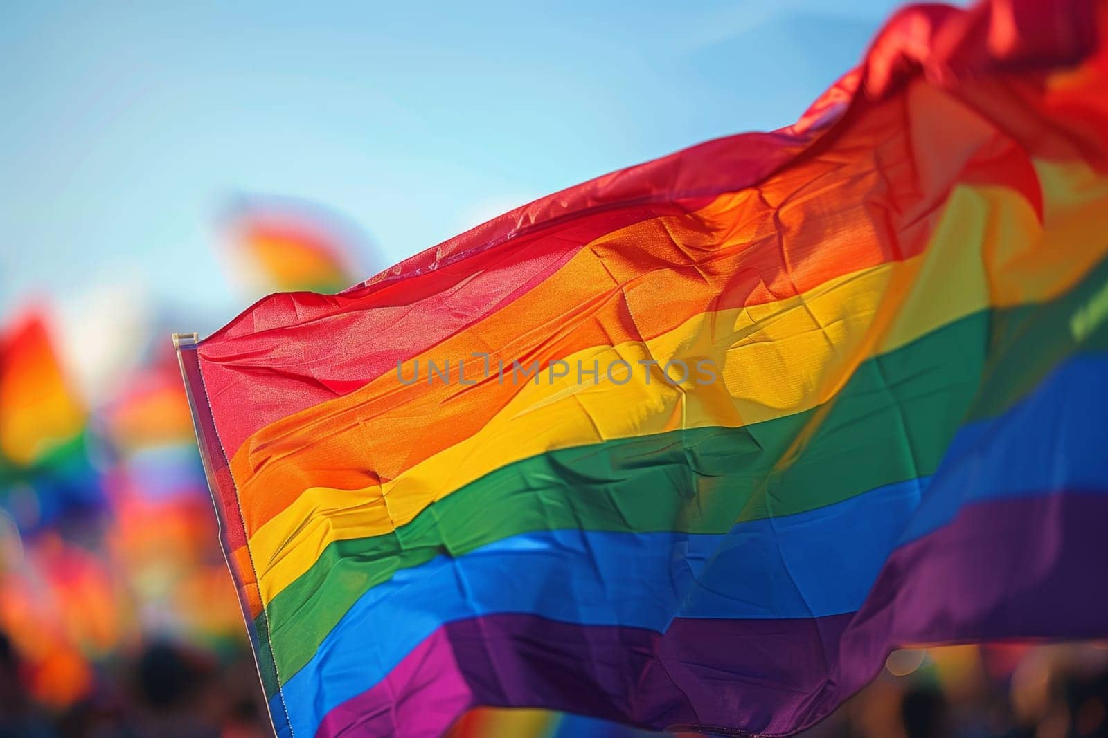 A rainbow LGBT flag flies against a blue sky.