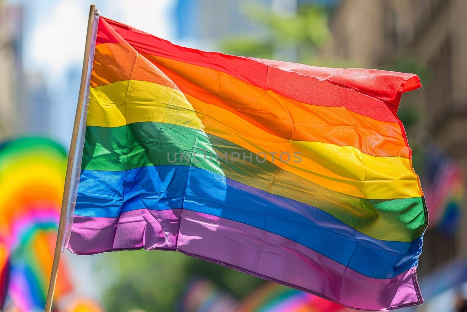 A rainbow LGBT flag flies against a blue sky.