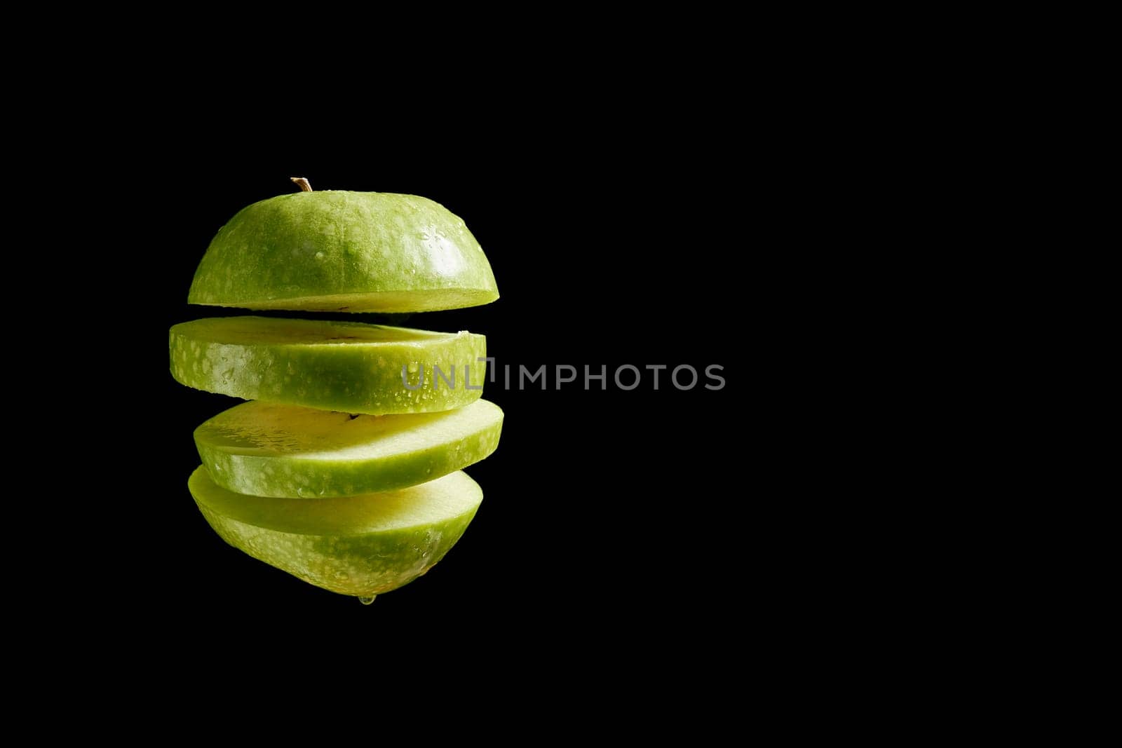 Sliced apple with water droplets over black background by superstellar