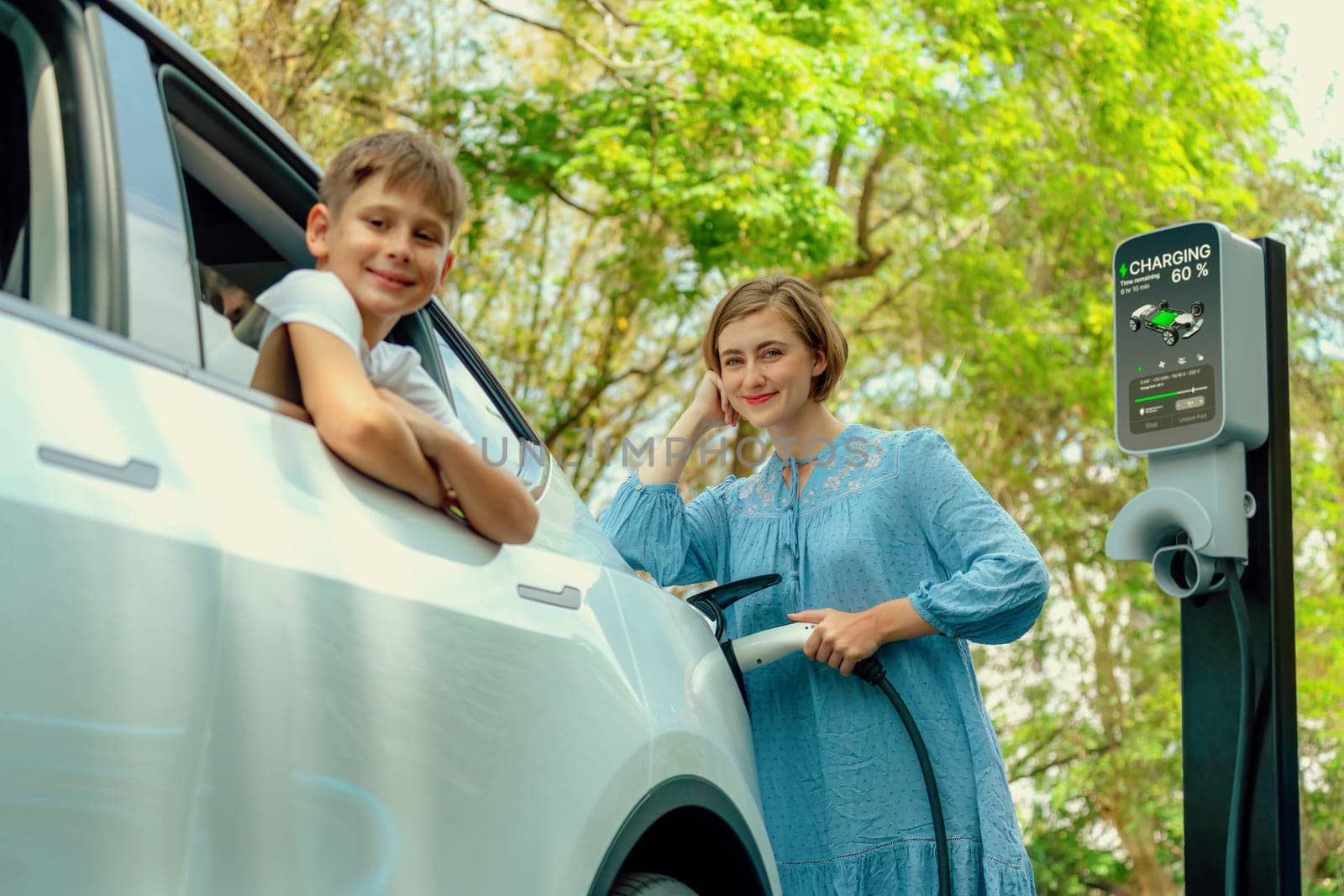 Family road trip vacation with electric vehicle, mother and son recharge EV car with green and clean energy. Nature and travel with eco-friendly car for sustainable environment. Perpetual