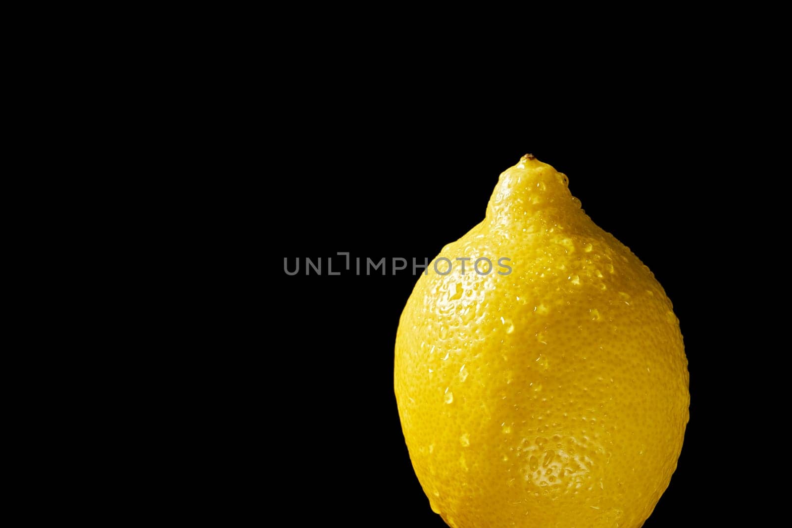 Close up of lemon with water droplets on black background by superstellar