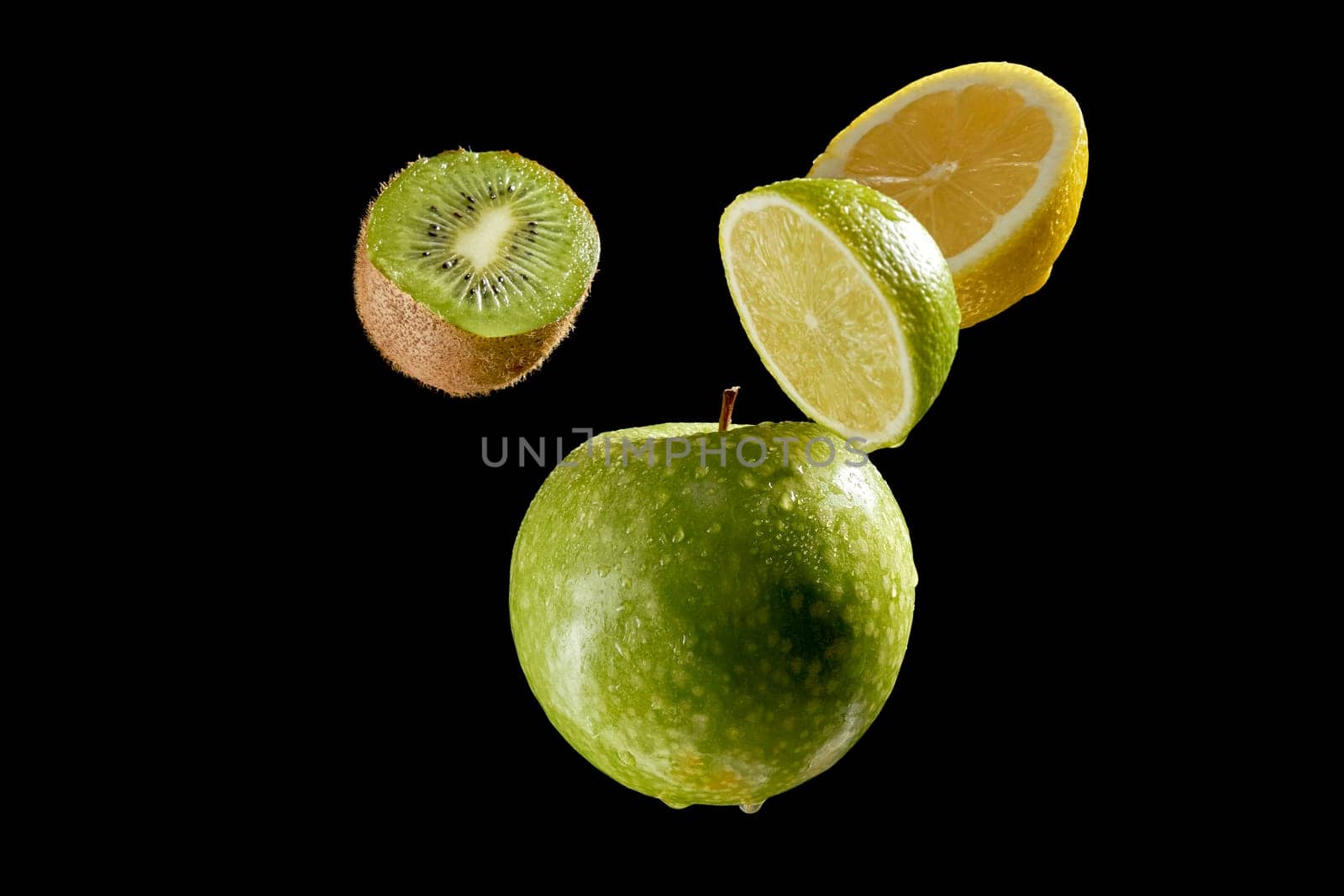 Green fresh fruits halves on black background by superstellar