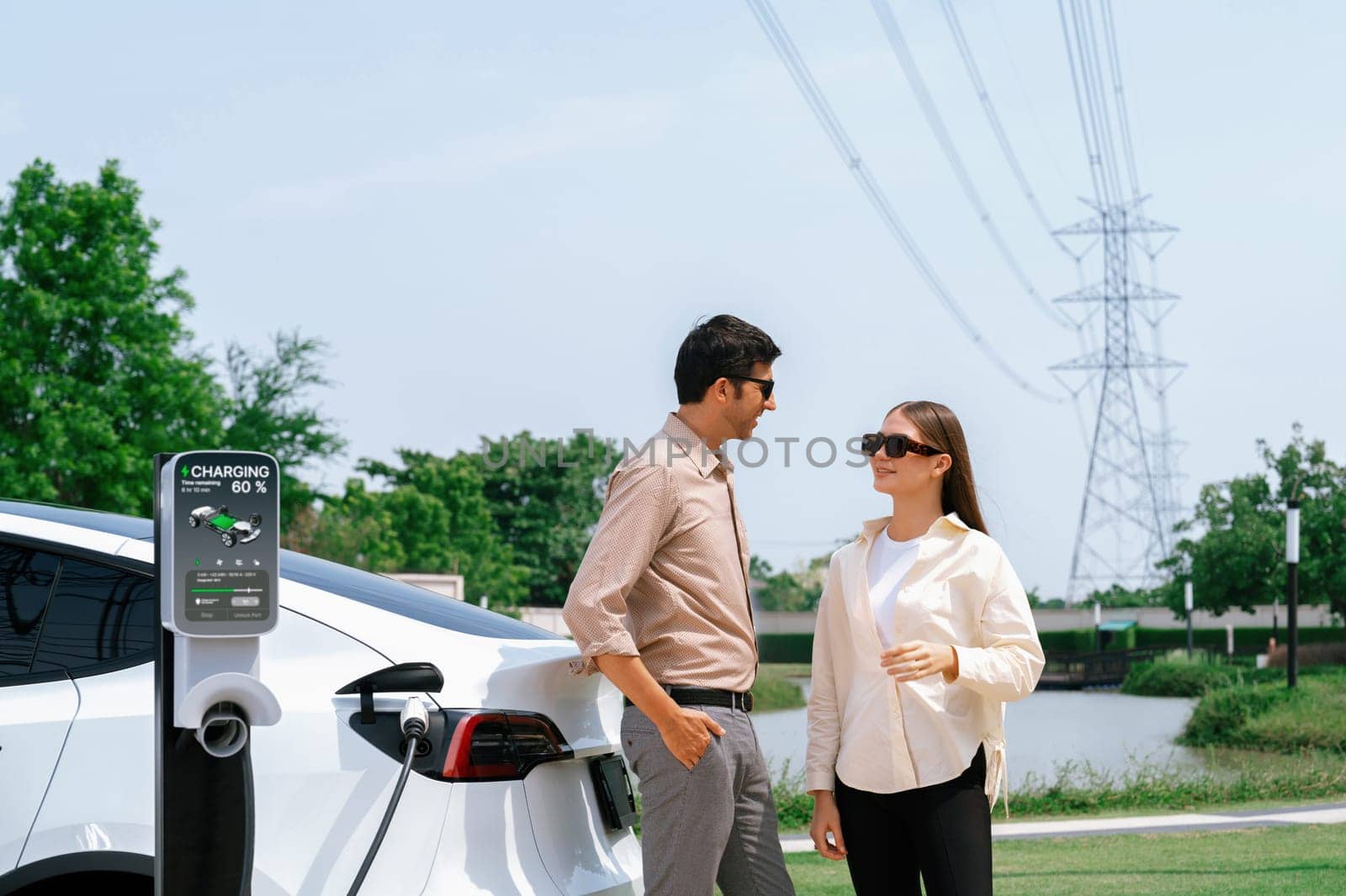 Young couple recharge EV car battery at charging station. Expedient by biancoblue