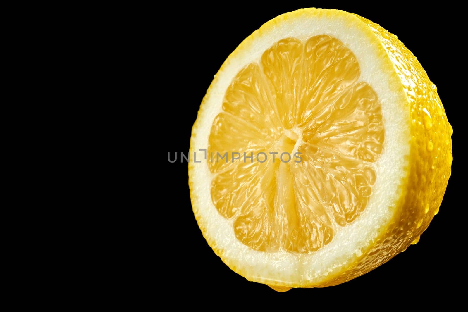 Closeup of fresh yellow organic half lemon with water droplets on black background