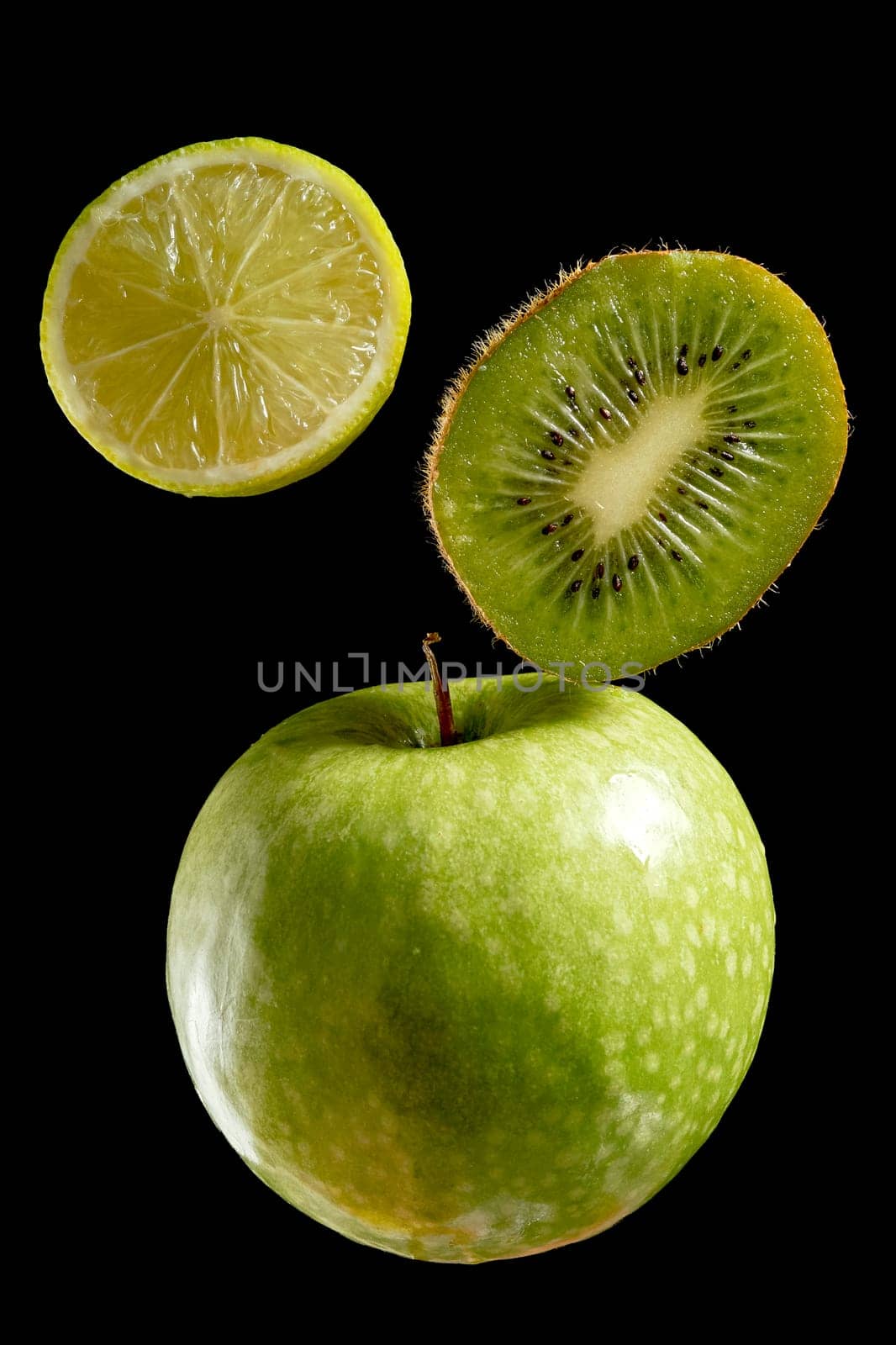 Green fresh organic fruits halves on black background