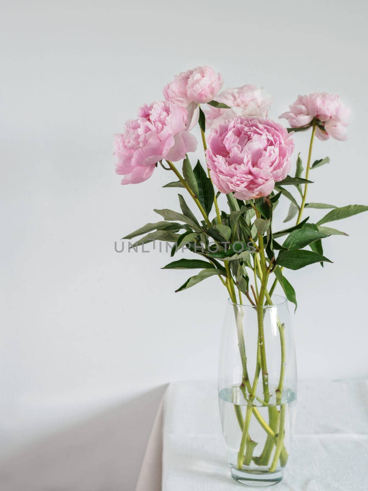 peony bouquet in vase on white table by fascinadora