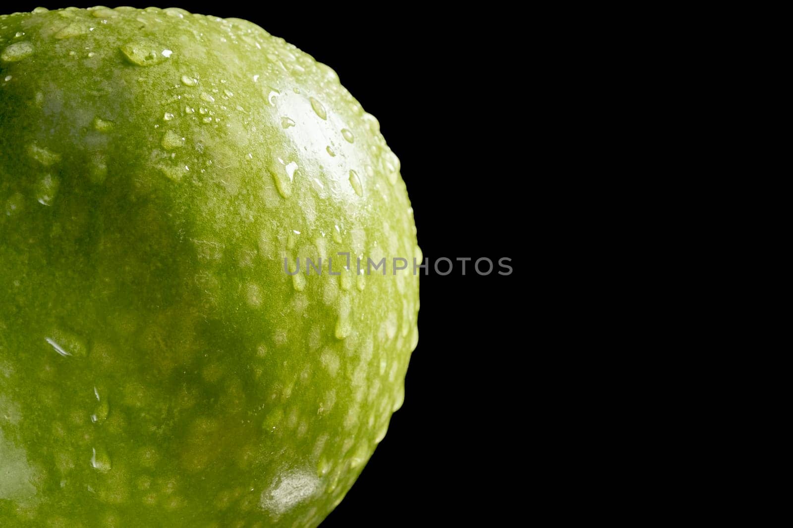 Close up of green organic fresh apple with water drops on black background