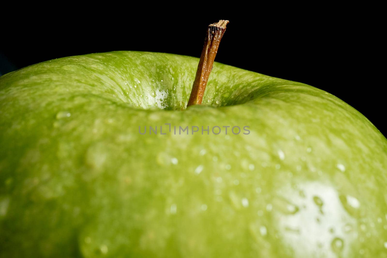 Close up of green organic fresh apple with water drops on black background