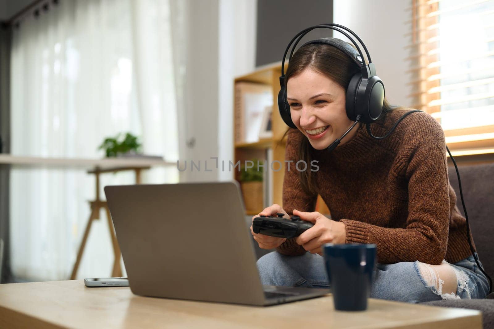 Young caucasian woman in headset holding joystick playing video game on laptop.