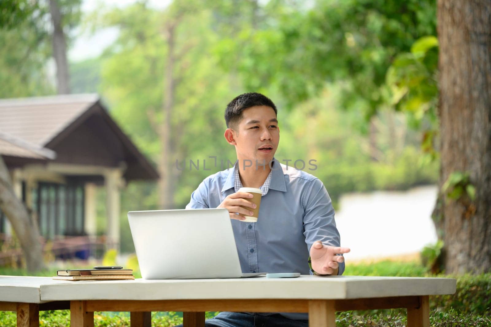Portrait of asian man entrepreneur drinking coffee and working with laptop at outdoor by prathanchorruangsak