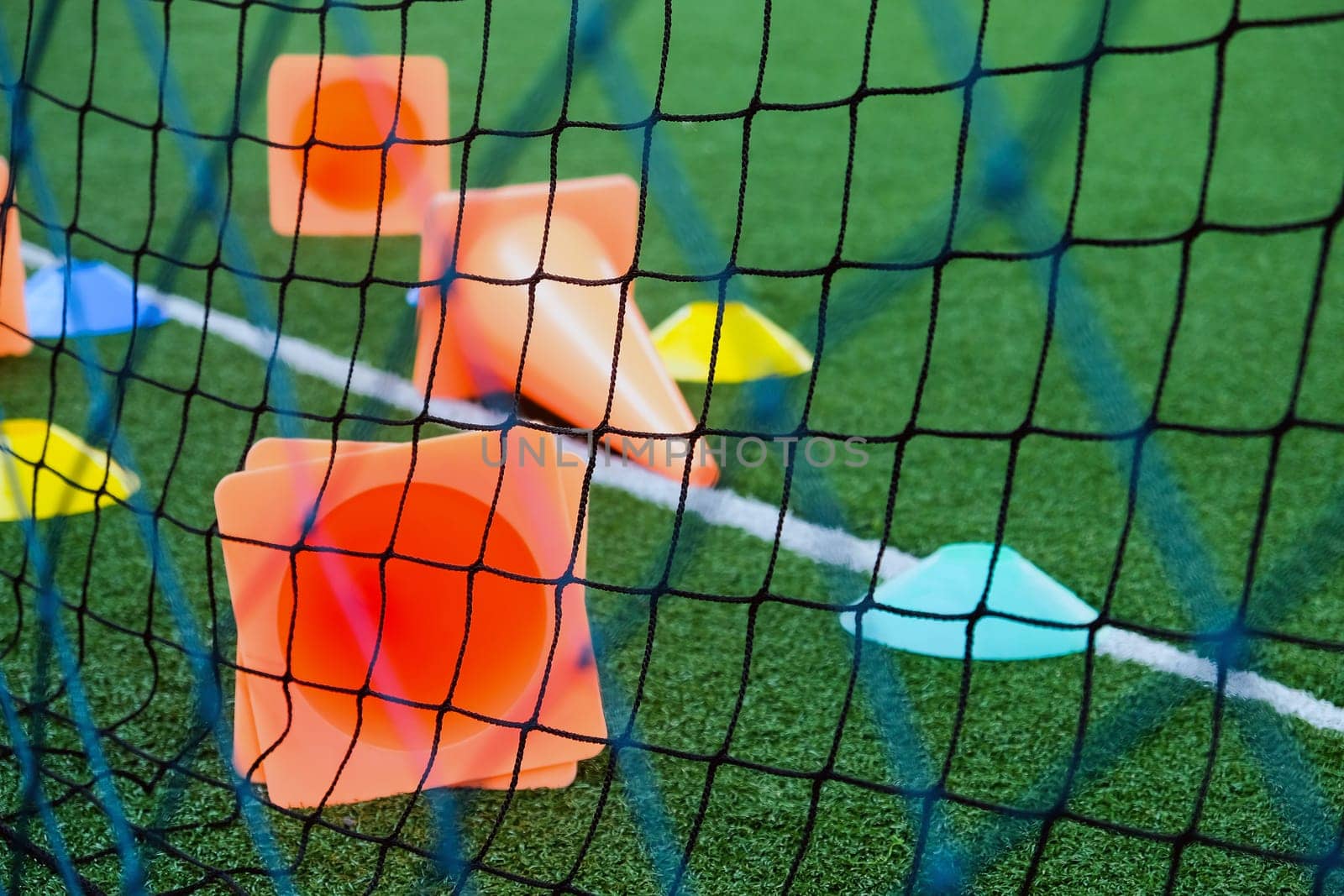 Soccer goal and cones on green artificial turf, sport background.