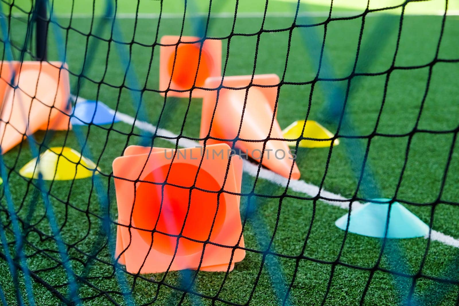 Soccer goal and cones on green artificial turf, sport background.