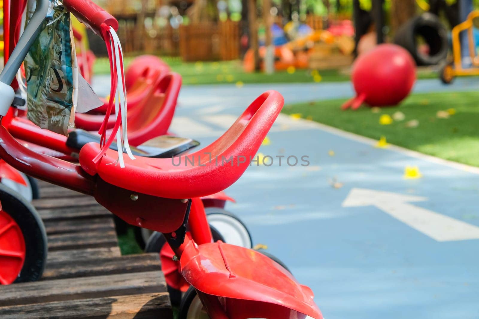 Playground with red toy car on green grass field in public park by ponsulak