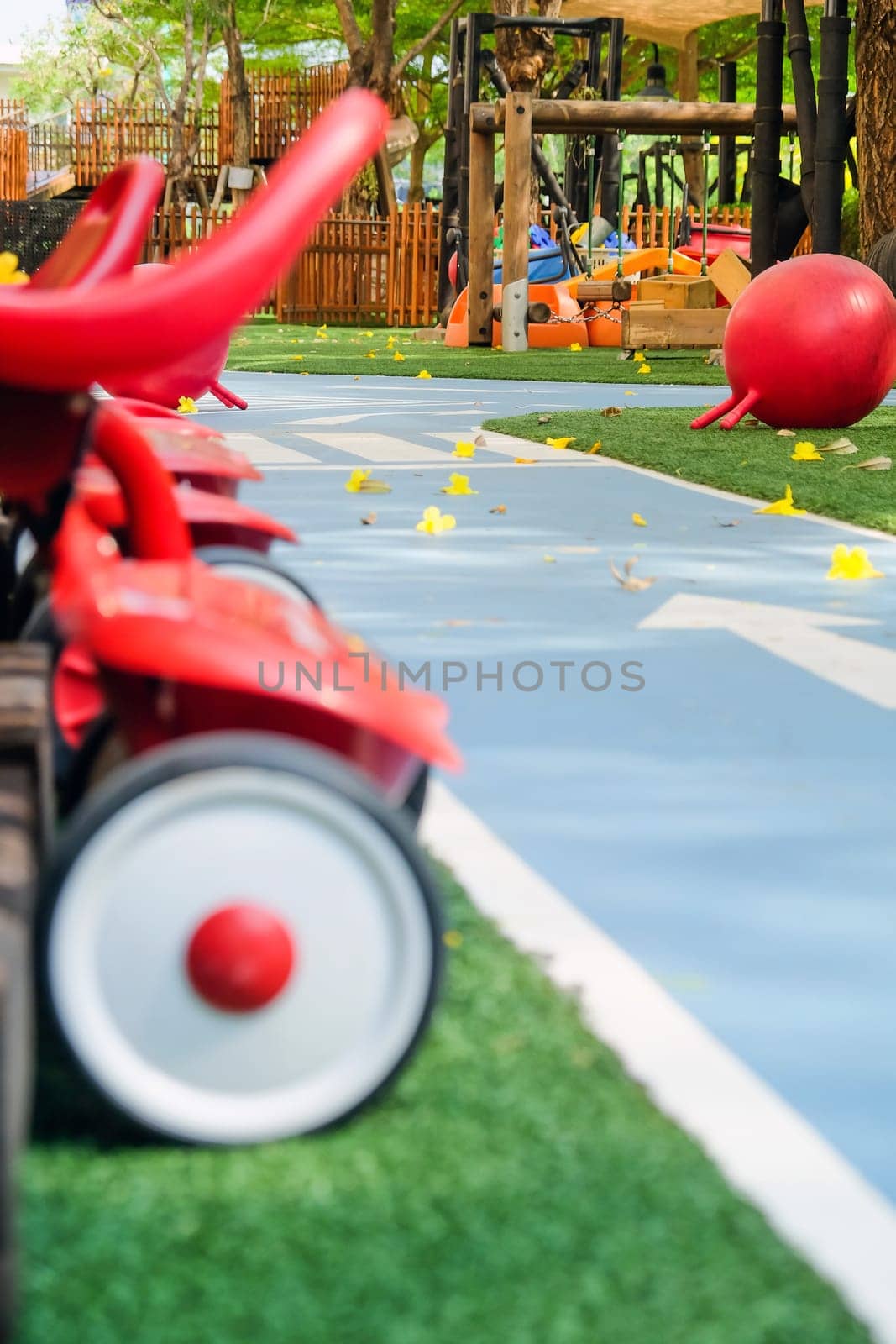 Playground with red toy car on green grass field in public park by ponsulak
