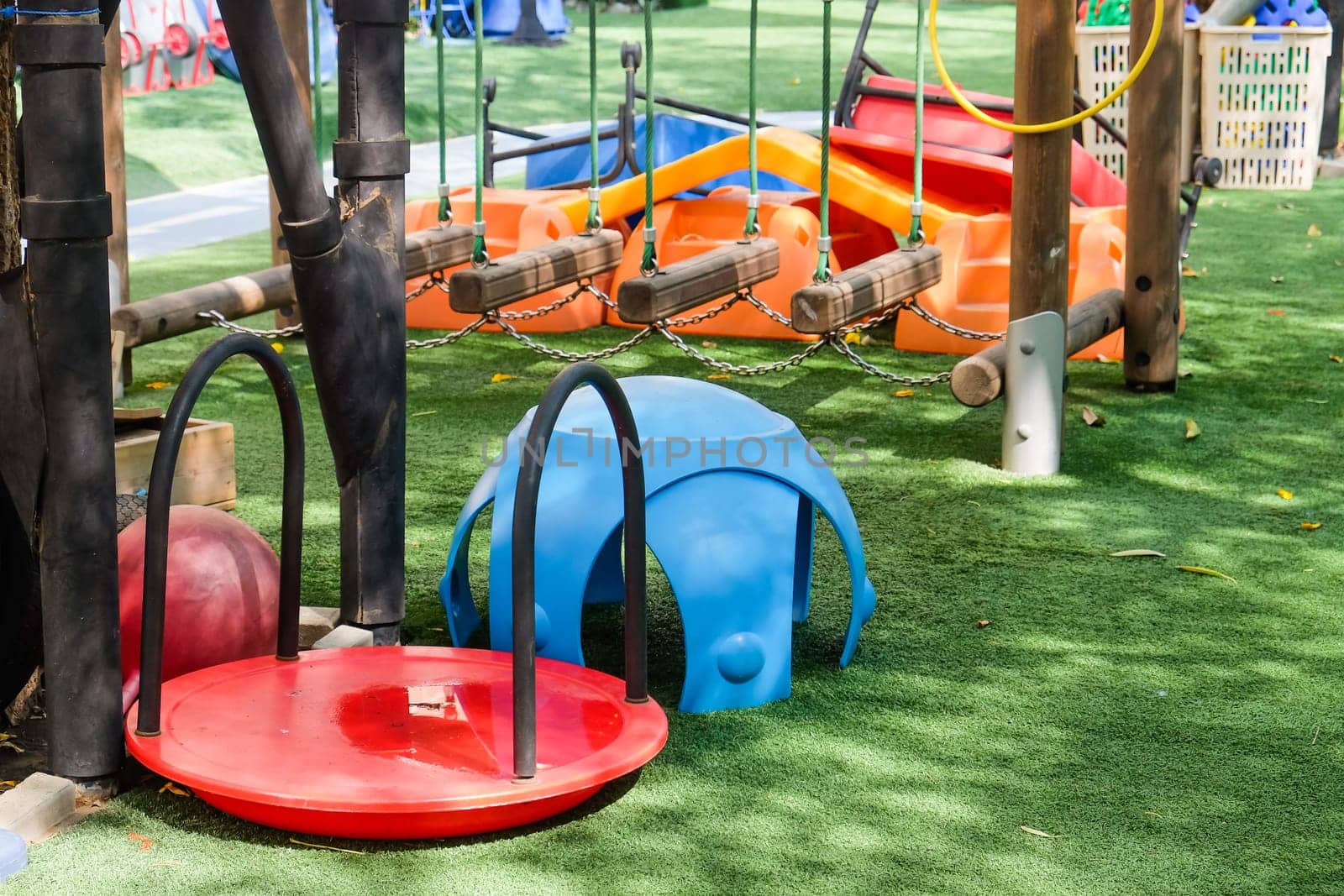 Playground in the park with blue and red seats and swings. by ponsulak