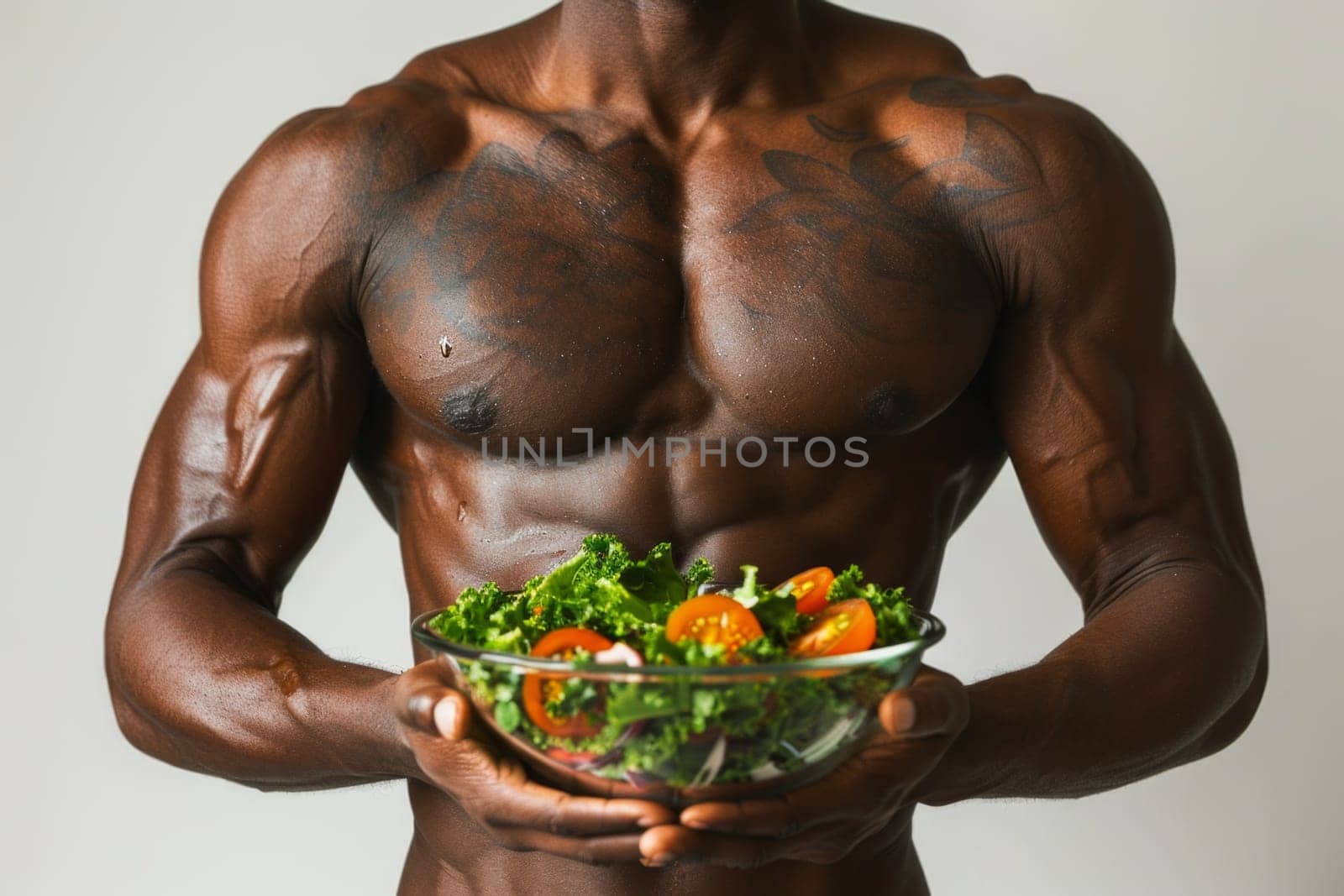 Portrait of strong male athlete torso holding a green salad. Concept of healthy food and lifestyle.