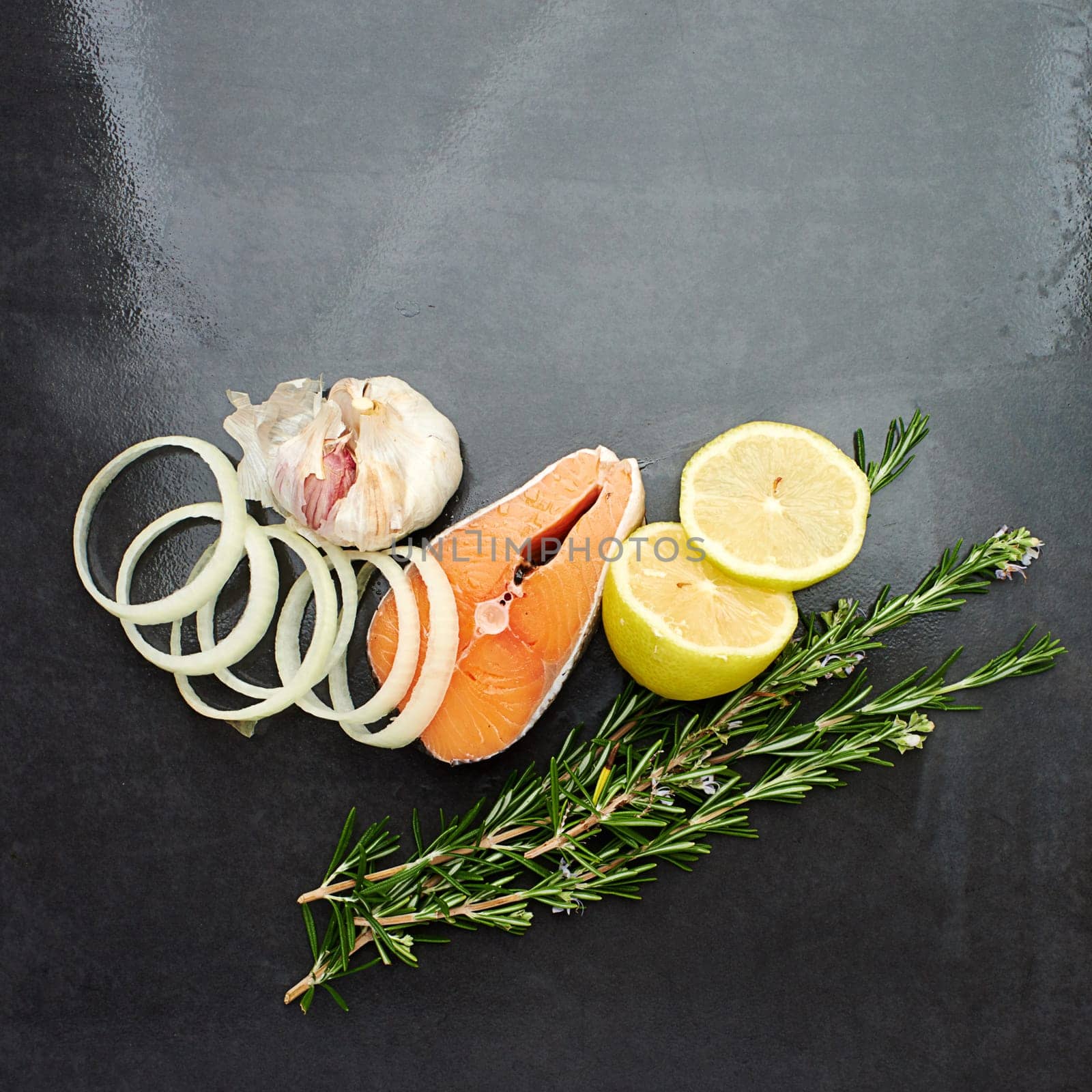 Organic, food and nutrition with salmon, garlic and lemon in kitchen or studio. Healthy eating and recipe for wellness, health and cuisine with fresh herbs or rosemary for cooking or meal preparation by YuriArcurs