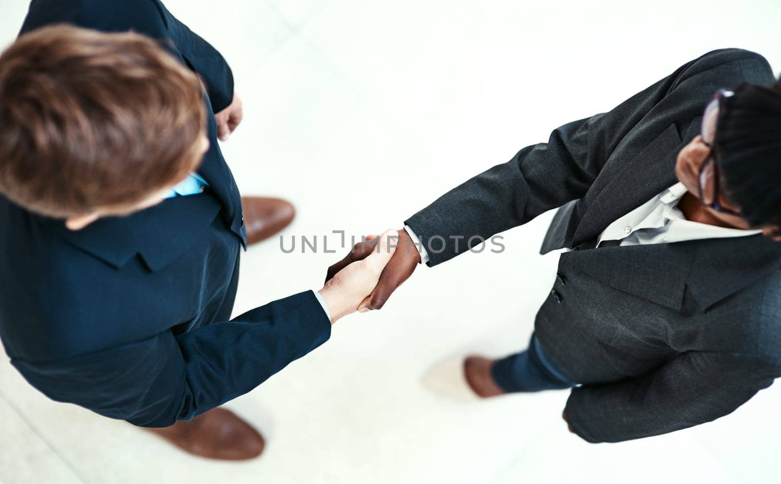 Diversity, handshake and partnership with business people in office for agreement or deal from above. Meeting, thank you or welcome with man and woman employee shaking hands in workplace for contract by YuriArcurs