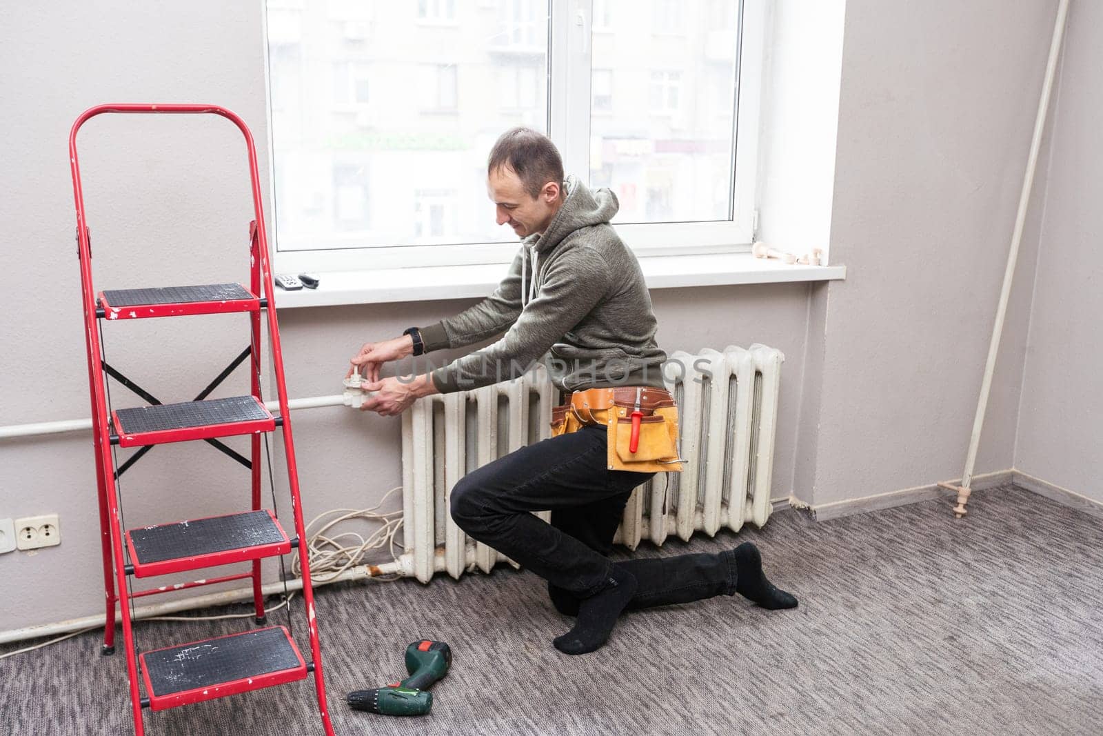 Worker replaces domestic radiator in the living room. High quality photo