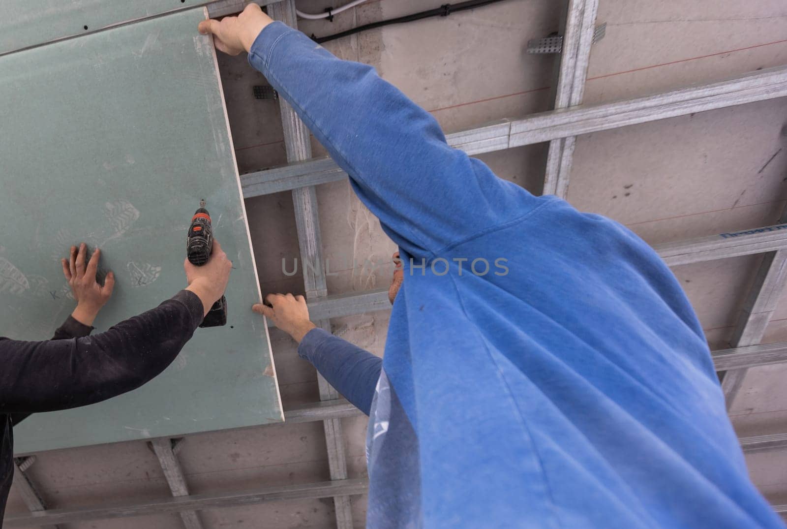 The wage workers set the ceiling profile in the new flat. High quality photo