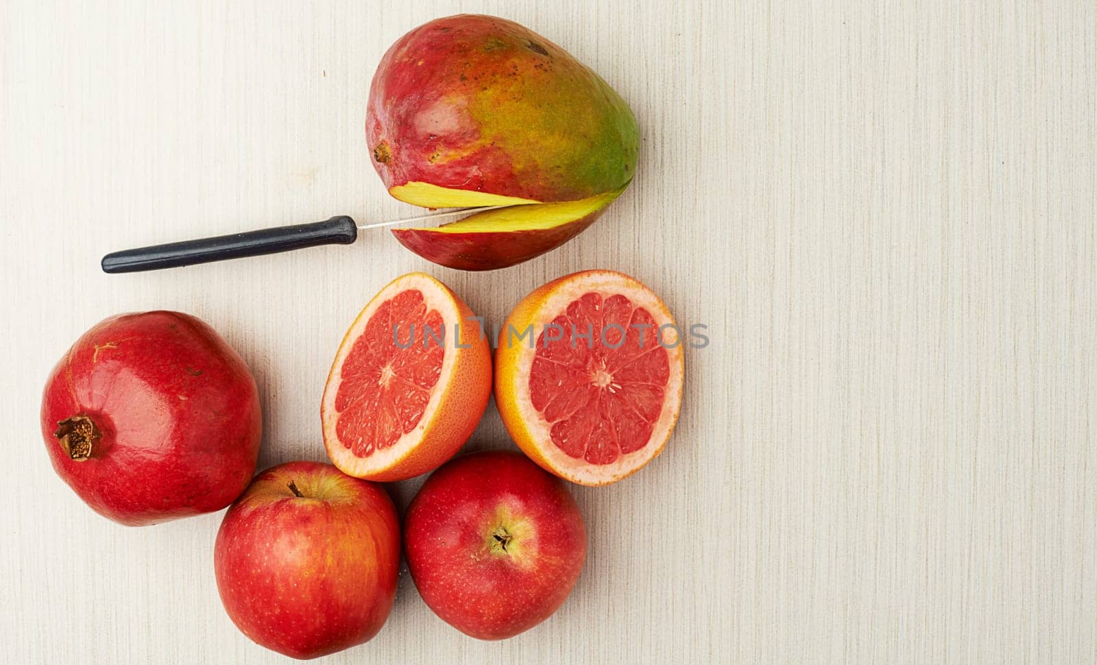 Fruit, nutrition and health on table top with knife for food, diet and wellness on studio background. Mango, vegan and vitamin c for cooking, eating and flat lay of grapefruit for mock up space