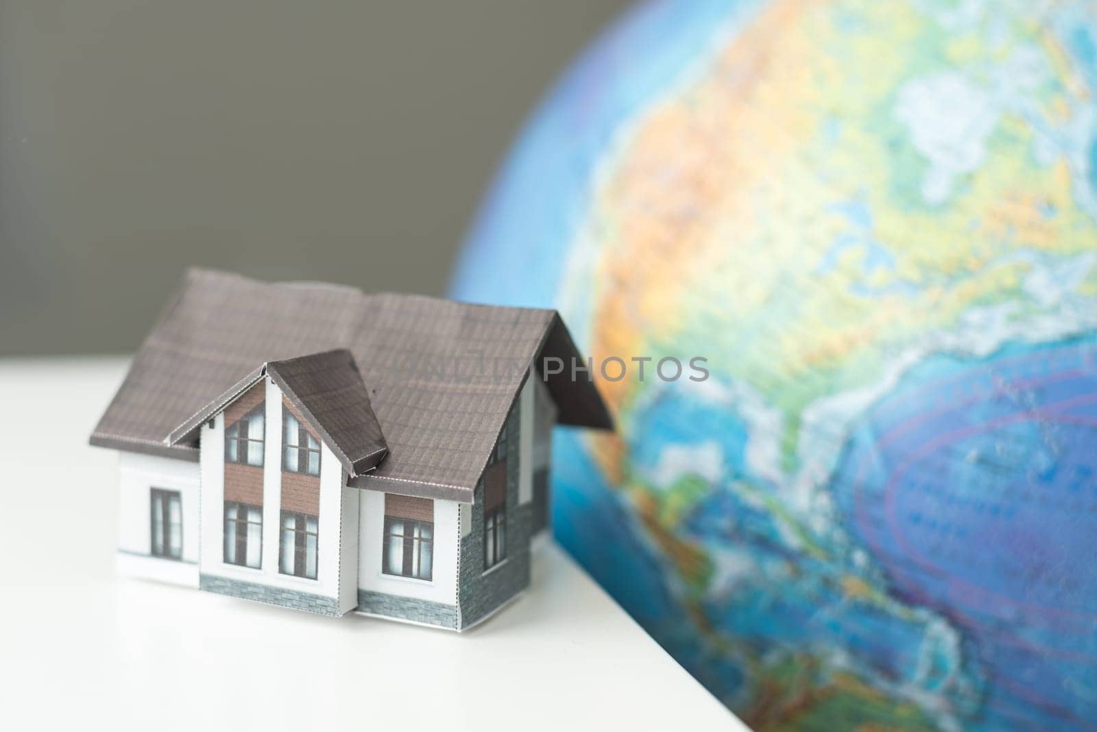 House miniature with globe in background against plain wall by Andelov13