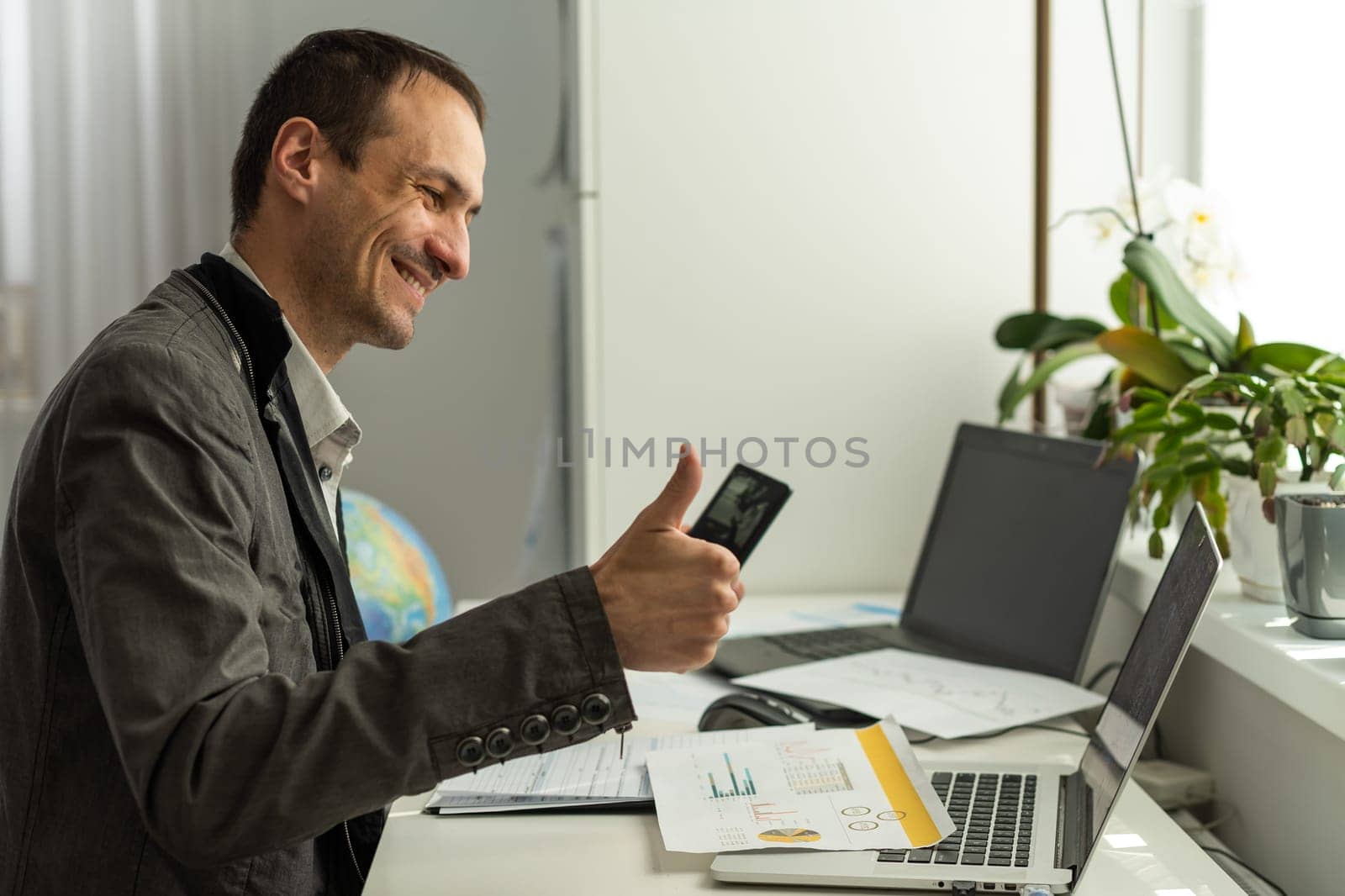 Financial video briefing. Friendly caucasian businessman, employee or financial manager, mentor, conducts video conference, online virtual meeting, shows graphs, while sitting in modern office, smiles. High quality photo