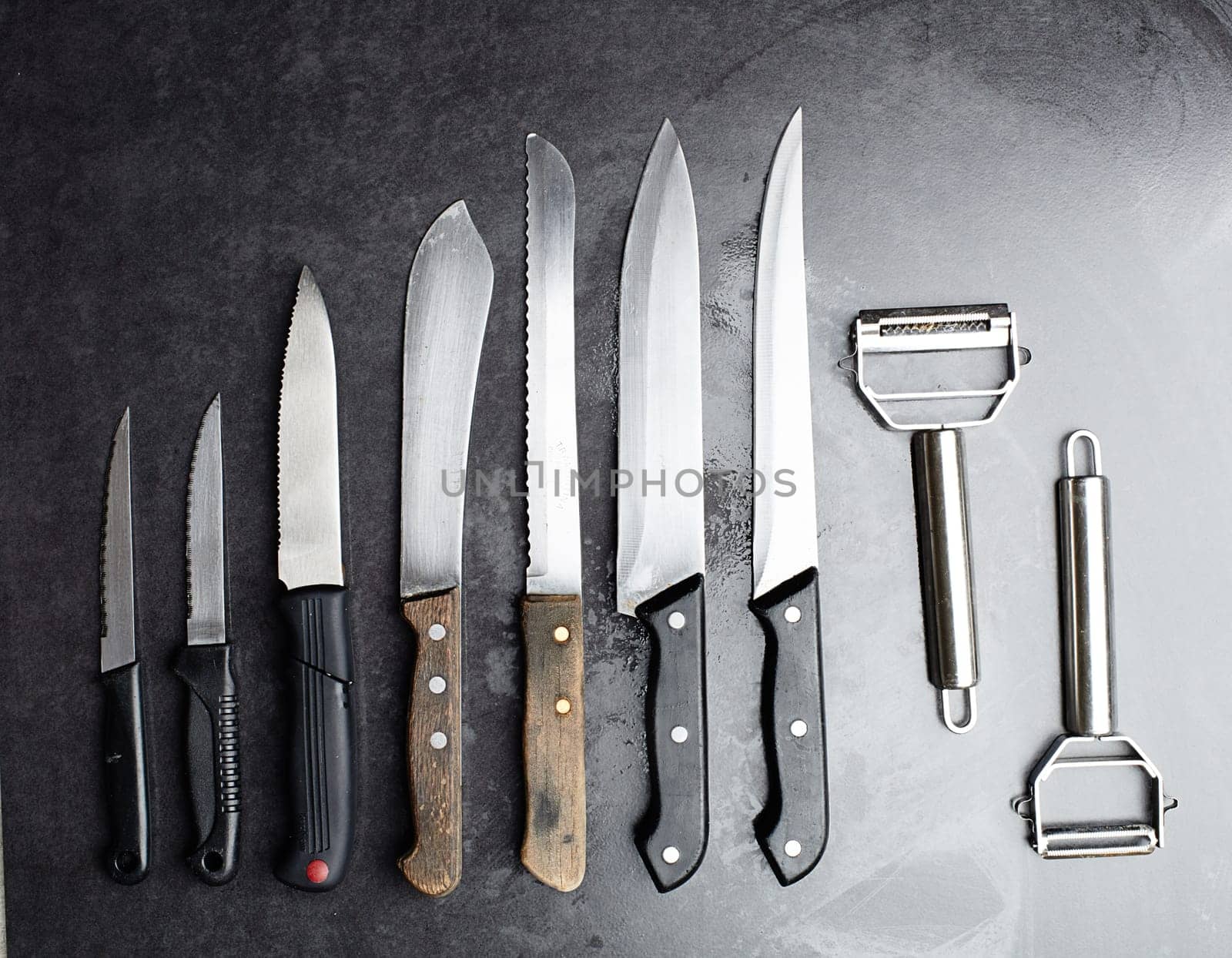 Knives, tools and kitchen equipment on table for professional chef, restaurant and culinary steel. Instrument, cutlery and blade for gourmet cafe, cutting and catering service in studio for meal prep by YuriArcurs