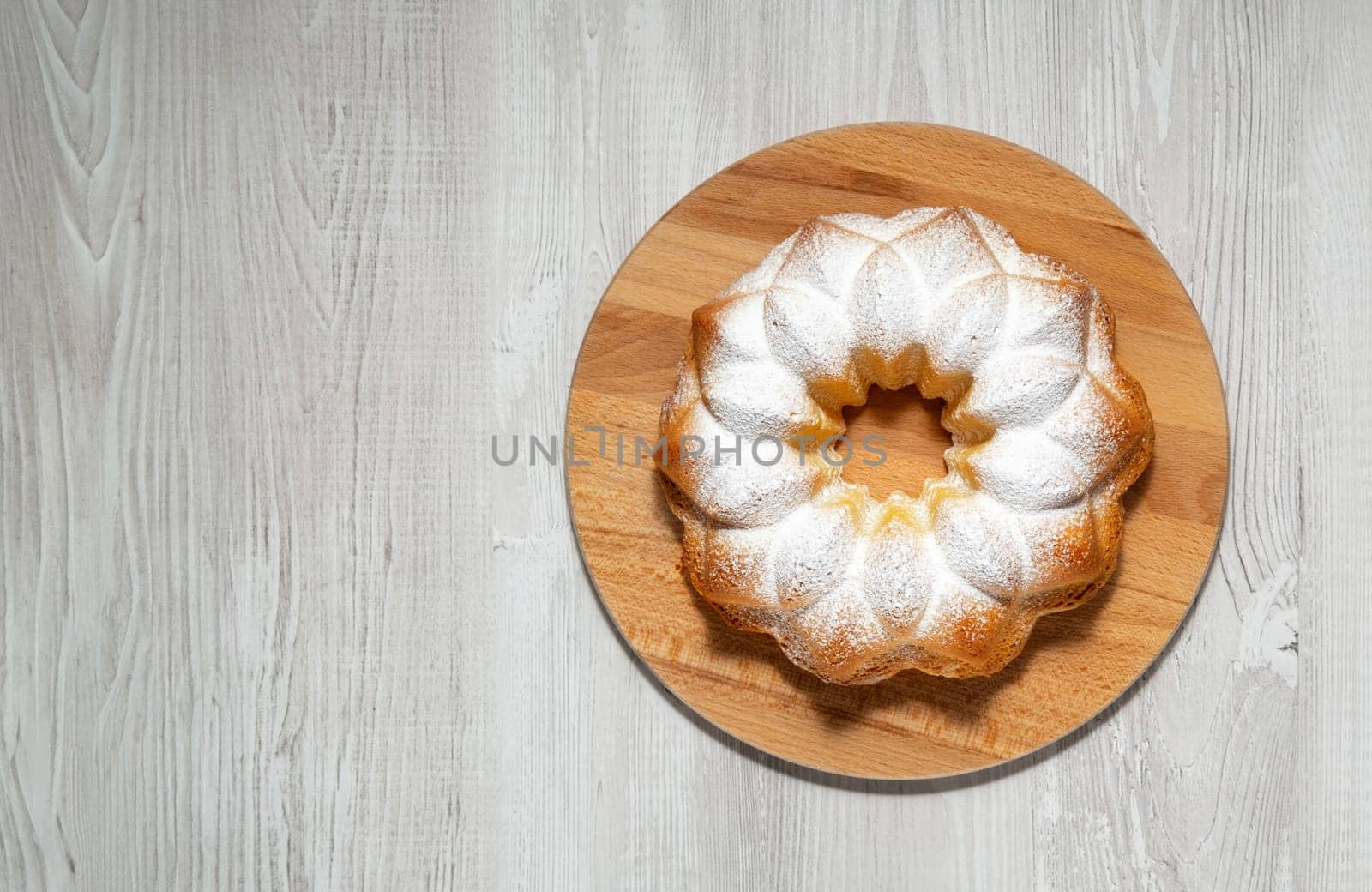 Homemade cupcake on a light wooden table.