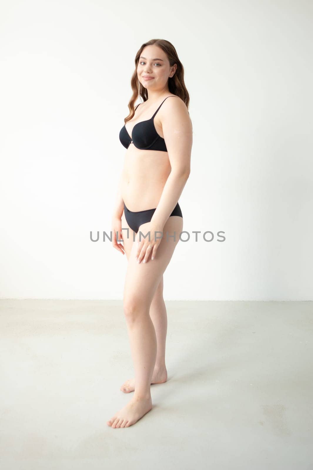 young woman with beautiful hair in black lingerie posing isolated on white background. Model test, snap, polaroid