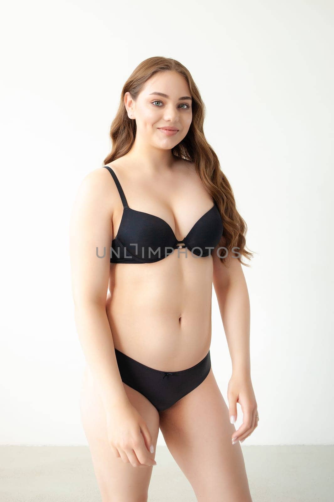 young woman with beautiful hair in black lingerie posing isolated on white background. Model test, snap, polaroid