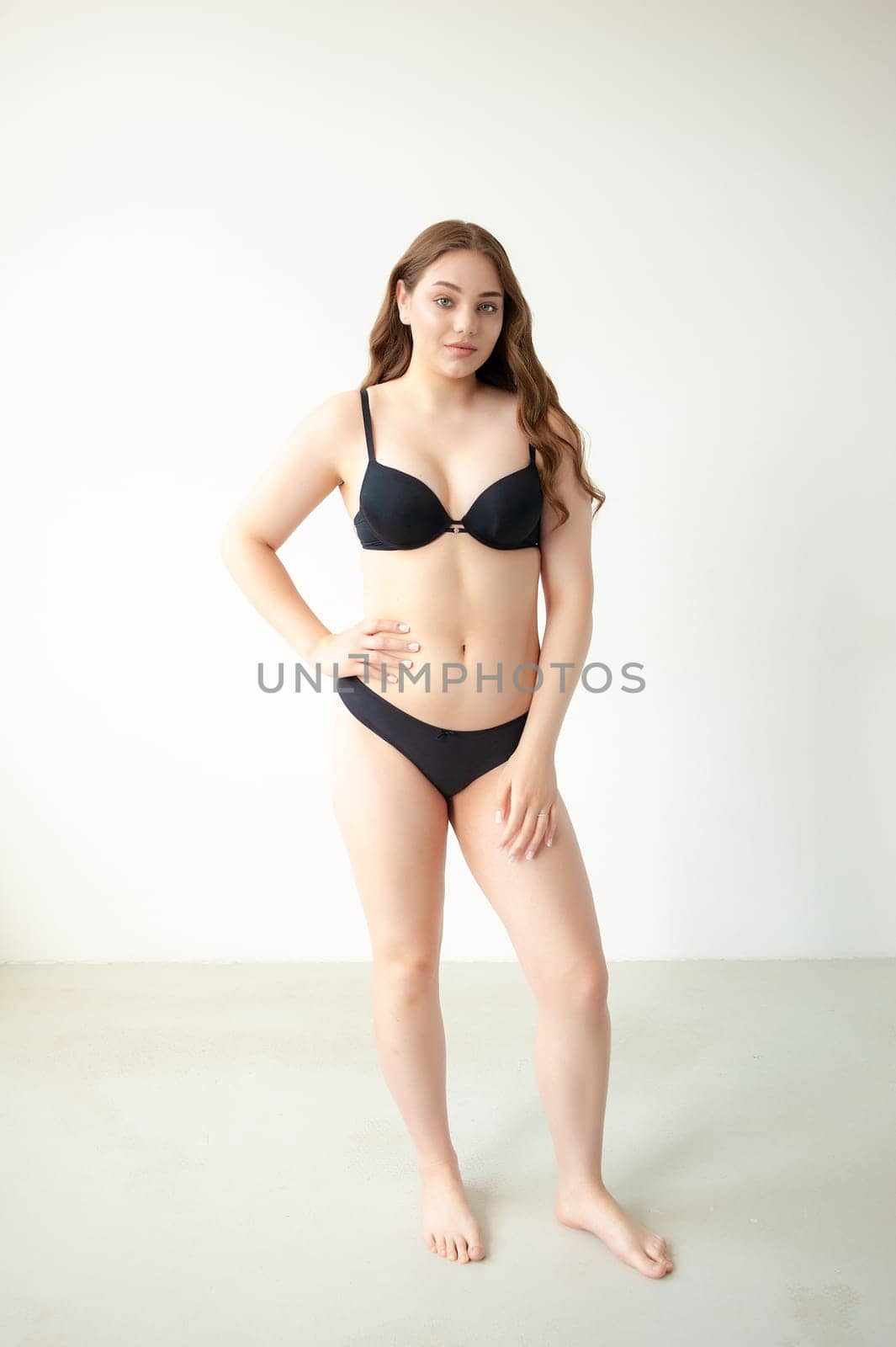 young woman with beautiful hair in black lingerie posing isolated on white background. Model test, snap, polaroid