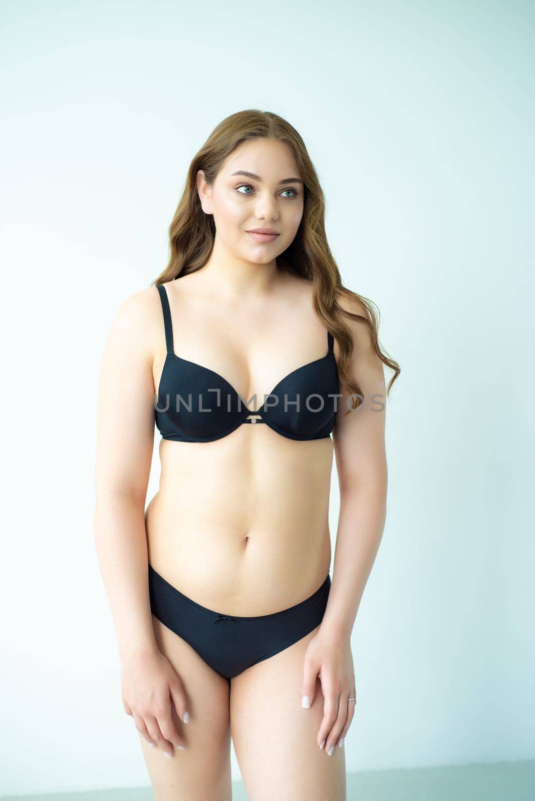 young woman with beautiful hair in black lingerie posing isolated on white background. Model test, snap, polaroid