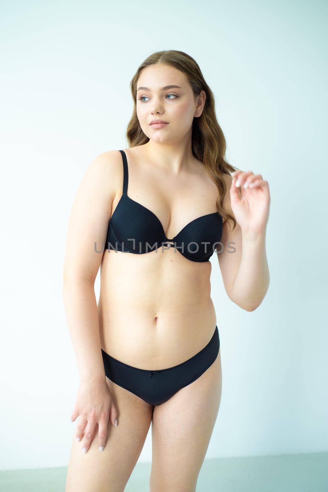 young woman with beautiful hair in black lingerie posing isolated on white background. Model test, snap, polaroid