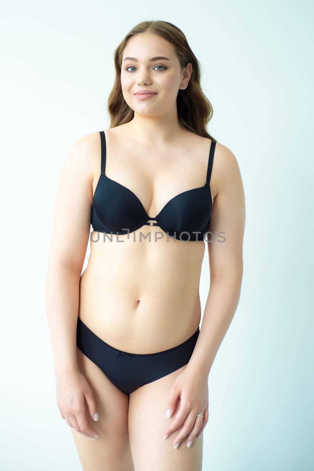 young woman with beautiful hair in black lingerie posing isolated on white background. Model test, snap, polaroid