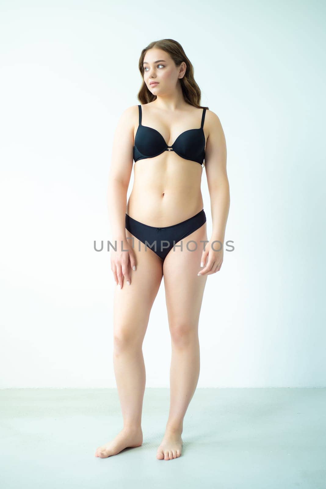 young woman with beautiful hair in black lingerie posing isolated on white background. Model test, snap, polaroid