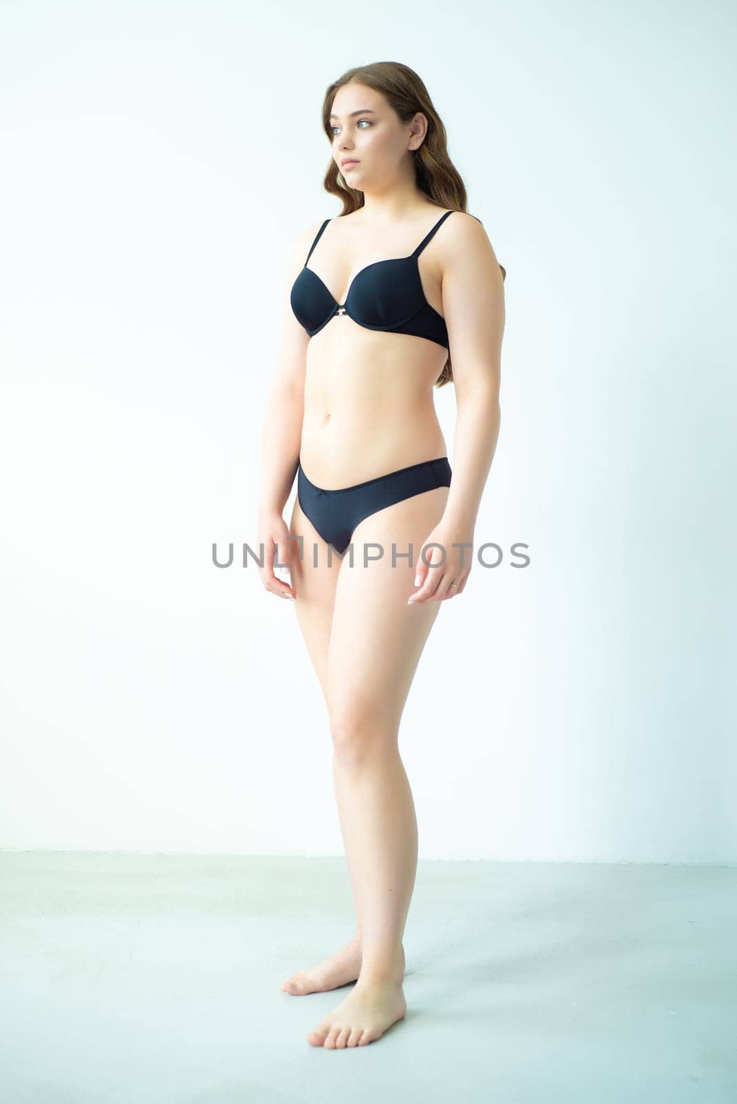 young woman with beautiful hair in black lingerie posing isolated on white background. Model test, snap, polaroid