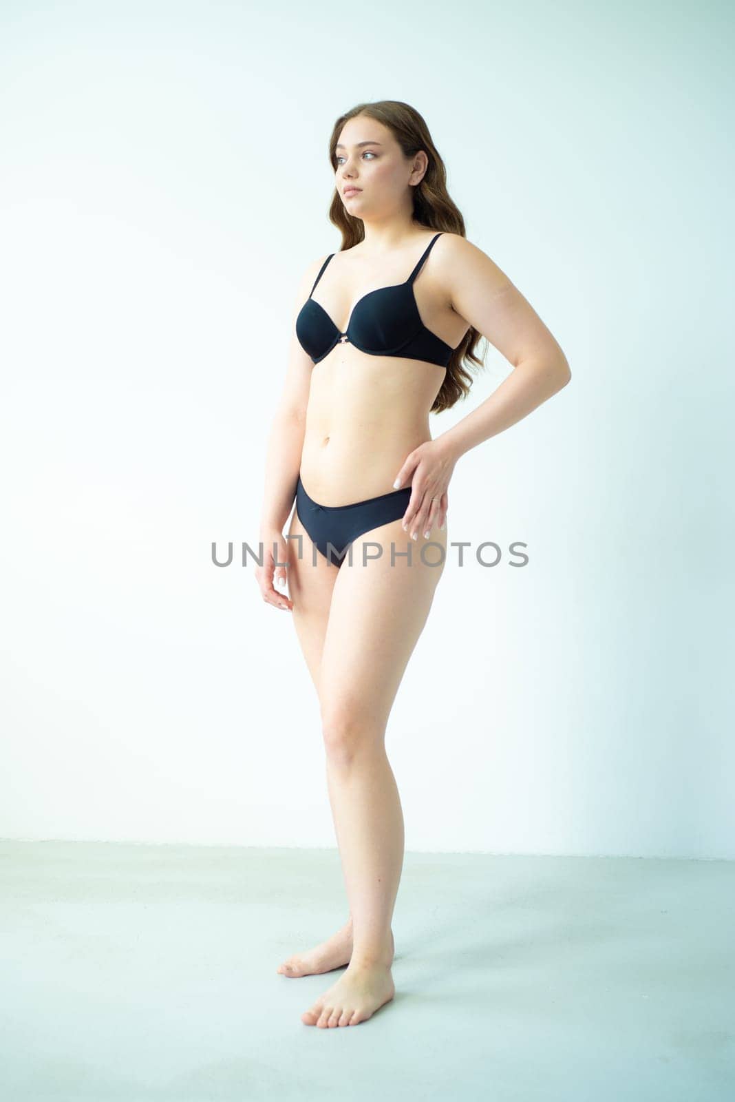 young woman with beautiful hair in black lingerie posing isolated on white background. Model test, snap, polaroid