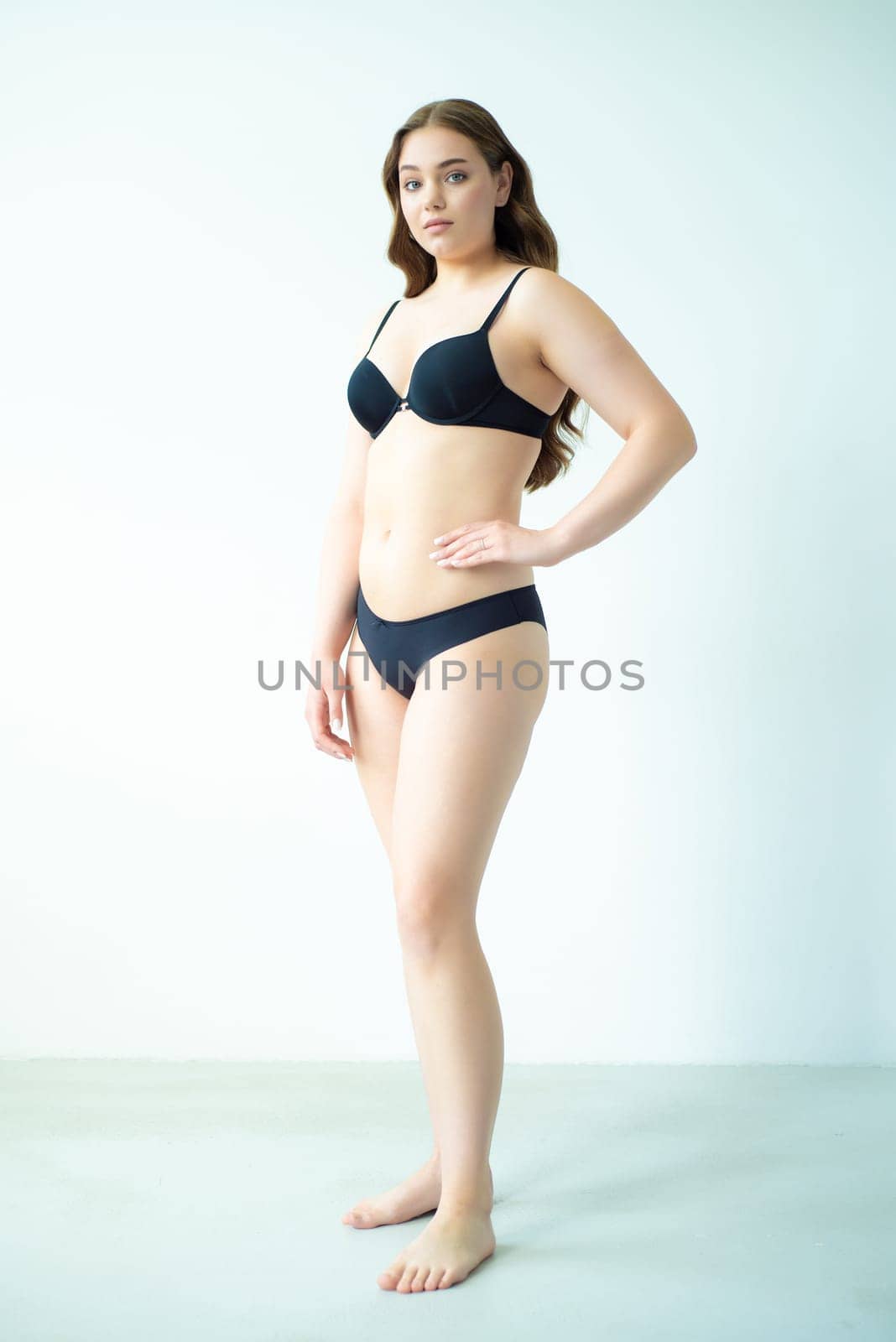 young woman with beautiful hair in black lingerie posing isolated on white background. Model test, snap, polaroid