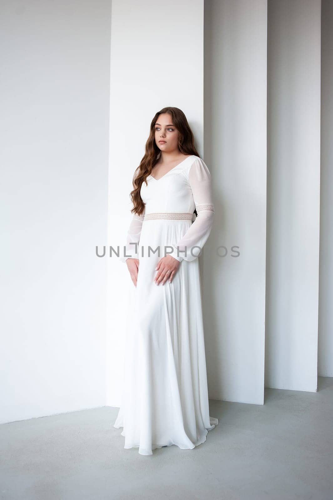 portrait of beautiful young woman in white wedding dress posing in studio. by OleksandrLipko