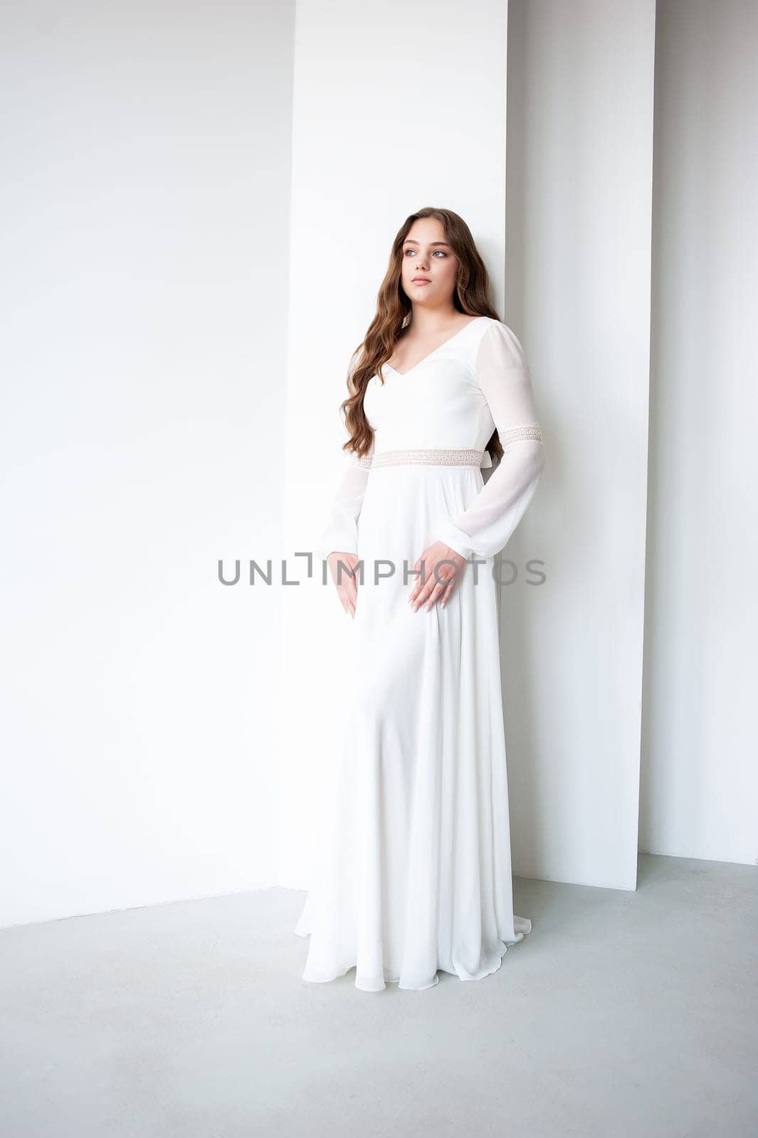 portrait of beautiful young woman in white wedding dress posing in studio. by OleksandrLipko