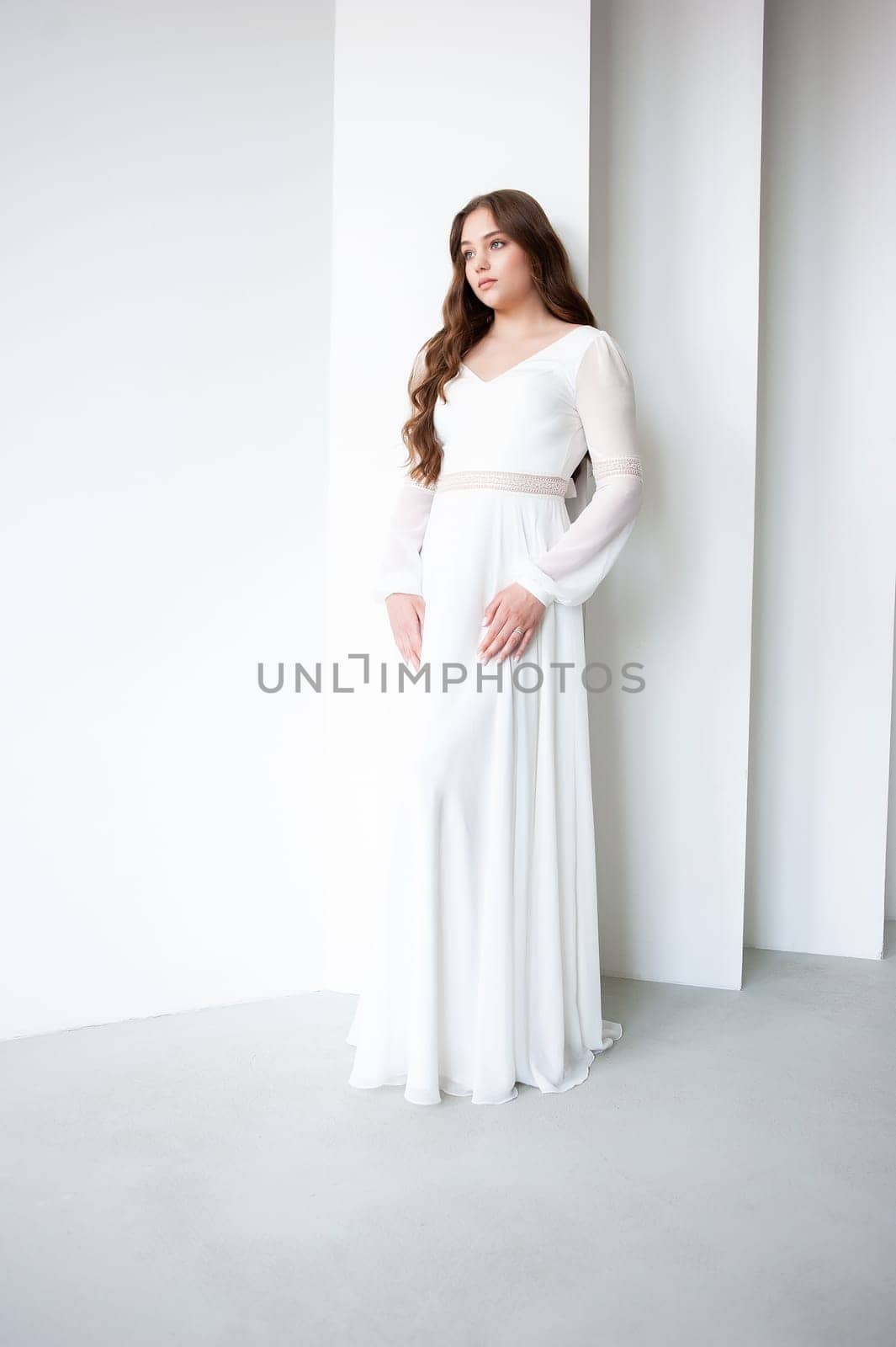 portrait of beautiful young woman in white wedding dress posing in studio. by OleksandrLipko