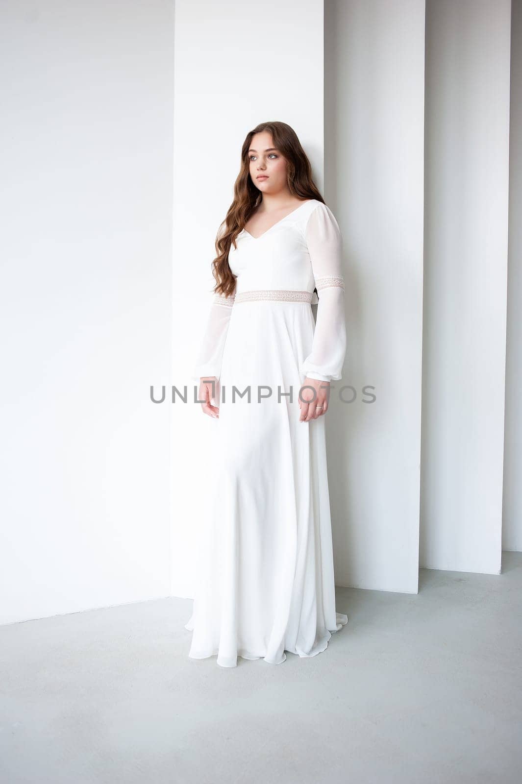 portrait of beautiful young woman in white wedding dress posing in studio